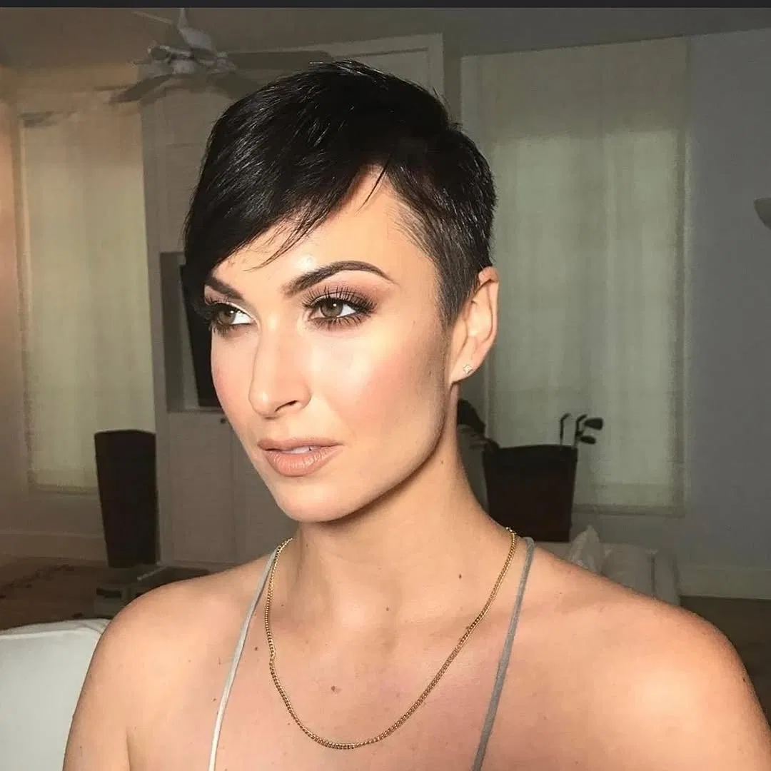 Short dark hair, a sculpted cheek, and a silver chain.